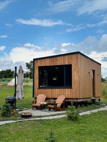 ein kleines Holzgebäude mit zwei Stühlen und einem Grill in der Unterkunft глемпінг Обійми in Yatski