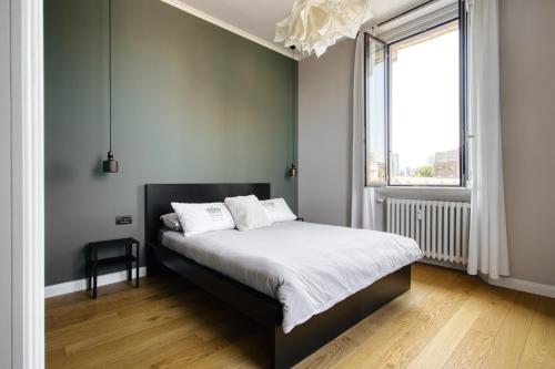 una camera da letto con un letto con lenzuola bianche e una finestra di Design & Dine a Milano