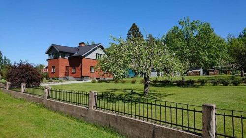 a fence in front of a house with a tree at Highland Hus in Hallstahammar