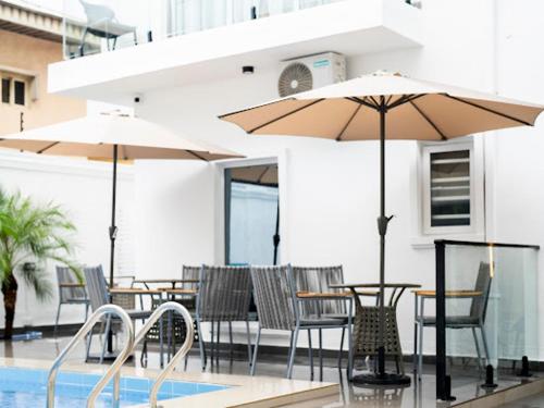 a patio with tables and chairs and umbrellas at Birch Hill Hotel Residence in Mama