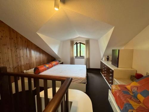 un dormitorio en el ático con una cama y una escalera en Accogliente Bilocale vicino Monte Pora - Presolana, en Malga Alta