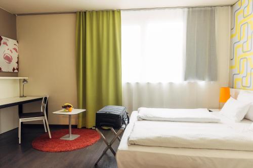a bedroom with two beds and a desk and a window at harry's home Dornbirn hotel & apartments in Dornbirn