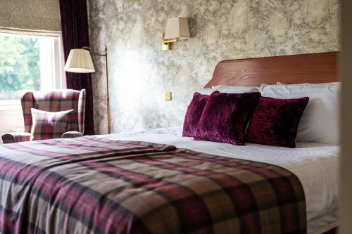 a hotel room with a bed with a plaid blanket at The Open Arms Hotel in Dirleton