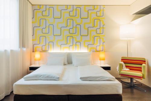 a bedroom with a bed and a yellow and white patterned wall at harry's home Dornbirn hotel & apartments in Dornbirn