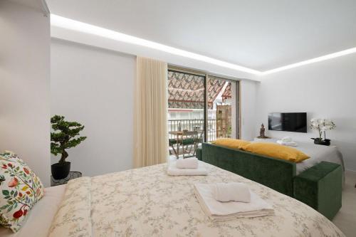 a bedroom with a large bed and a green couch at Amazonico - Proche Centre - Clim - Plage in Menton