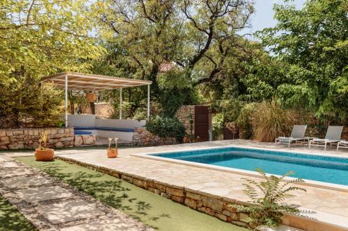 a swimming pool in a yard with a stone wall at Villa Estelle, Hvar Island in Vrbanj