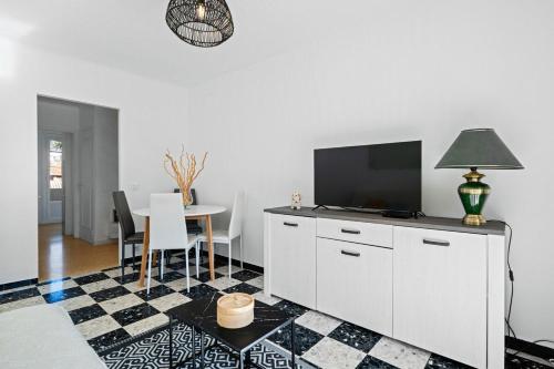 a living room with a tv on a white cabinet at LE STELLA - Central - Terrasse - Parking privé - Wifi in Roquebrune-Cap-Martin
