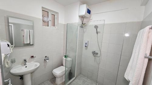 a bathroom with a shower and a toilet and a sink at Malika Nungwi Hotel in Nungwi
