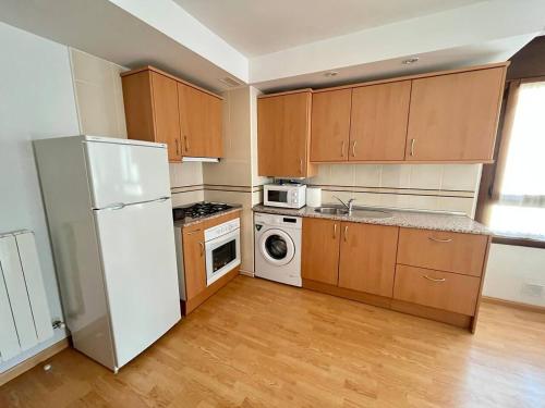 a kitchen with wooden cabinets and a white refrigerator at Apartamento Alma de Biescas in Biescas