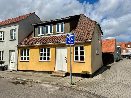 a yellow house with a blue sign in front of it at Kaj Munks Gade 19 - 3 værelses - 98m2 in Maribo
