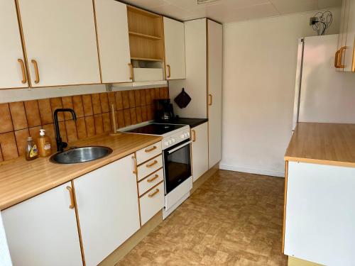 a kitchen with white cabinets and a sink and a refrigerator at Kaj Munks Gade 19 - 3 værelses - 98m2 in Maribo