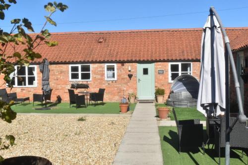 a house with an umbrella and a table and chairs at Swallow cottage in Louth