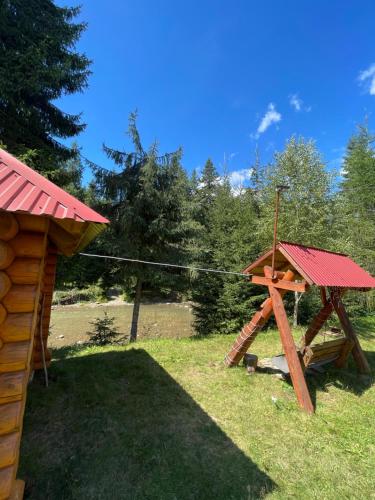 a wooden play structure in the grass next to a house at Садиба Урочище Луг in Vorokhta