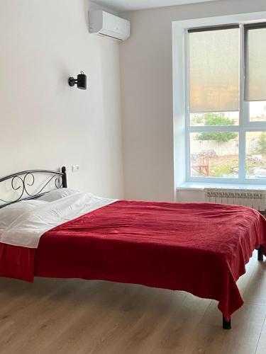 une chambre avec un lit avec une couverture rouge dessus dans l'établissement Квартира біля моря Чорноморськ, à Tchornomorsk