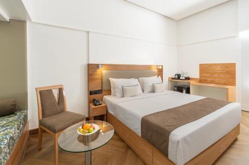 a bedroom with a bed and a chair and a table at Hotel Kohinoor Continental, Airport - Newly Renovated in Mumbai