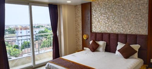 a bedroom with a bed and a large window at Hotel Imperial Inn in Patna