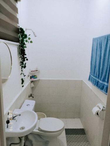 a bathroom with a white toilet and a sink at Sorelle- a cozy home in Manolo Fortich