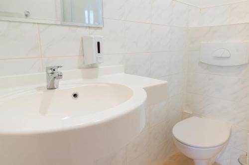 a white bathroom with a sink and a toilet at Hotel Victory Home in Warsaw