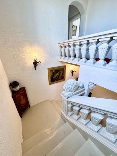 a staircase in a house with white stairs and a mirror at Palazzo dei Fiori since 1883 in Ħal Balzan
