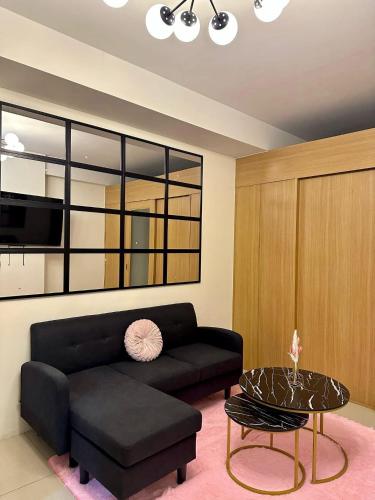 a living room with a black couch and a table at Staycation Near Mall of Asia in Manila