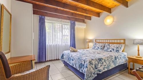 a bedroom with a bed and a desk and a window at Emerald Cove in Shelly Beach