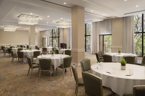 a dining room with white tables and chairs and windows at Sheraton Universal in Los Angeles