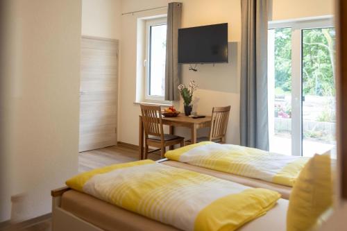 a bedroom with two beds and a table and a television at Ferienwohnungen im Waldhaus Sebnitz in Sebnitz