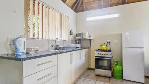 a kitchen with white cabinets and a white refrigerator at Emerald Cove in Shelly Beach
