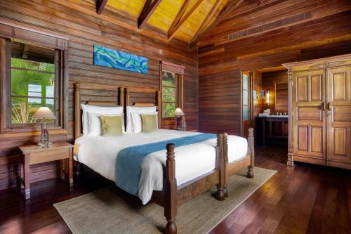 a bedroom with a bed in a room with wooden walls at JA Enchanted Island Resort Seychelles in Round Island