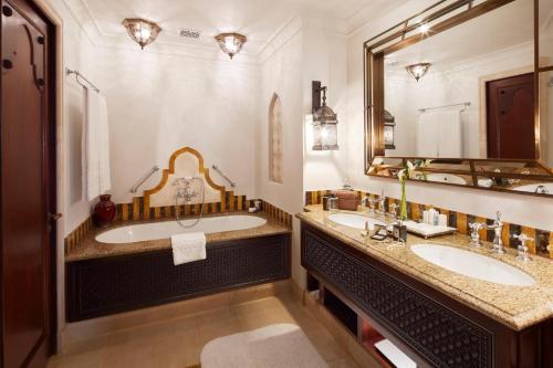 a bathroom with two sinks and a large mirror at Jumeirah Al Qasr Dubai in Dubai