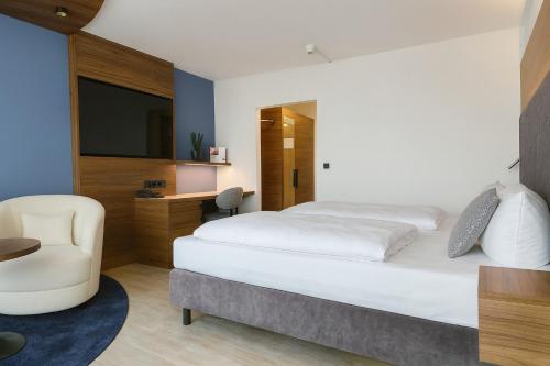 a hotel room with a bed and a chair at Johannesbad Hotel Königshof in Bad Füssing