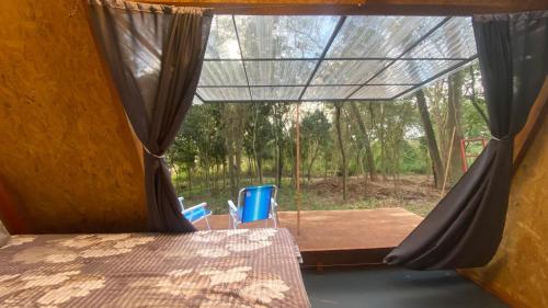 a room with a bed and a window with chairs at Chalecitos del Carmen in Carmen del Paraná