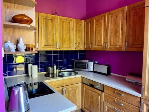 a kitchen with purple walls and wooden cabinets at Jasny Dwór in Polanica-Zdrój