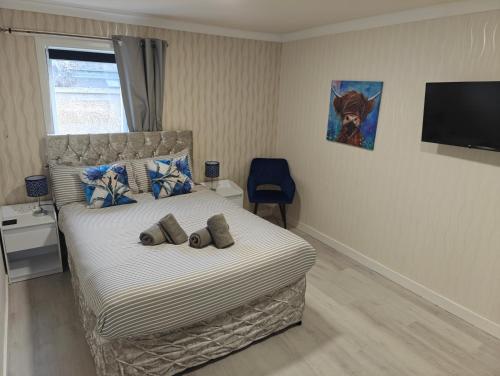 a bedroom with a bed with a chair and a television at The Jays Guest House in Aberdeen