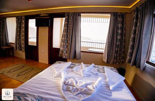 a bedroom with a bed with white sheets and a window at Sky Sail Dahabiya in Aswan