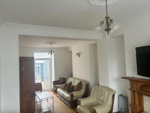 a living room with two chairs and a flat screen tv at The Greenfield Inn Guest House in Llanelli