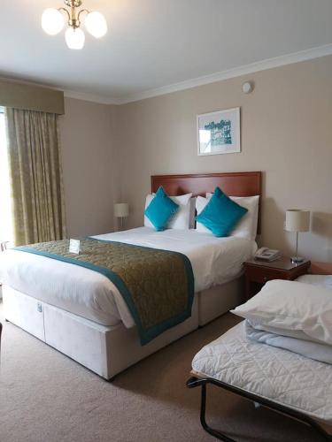 a hotel room with two beds with blue pillows at Les Rocquettes Hotel in St Peter Port
