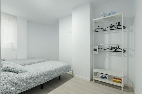 Un dormitorio blanco con una cama y un espejo. en Apartamento New Metro 6pax, en Rivas-Vaciamadrid