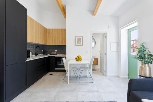 a kitchen with black cabinets and a white table at Bright Flat | Romantic Escape by HostWise in Porto