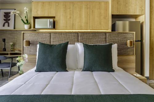 a bedroom with a large white bed with green pillows at NH Guadalajara Studios in Guadalajara