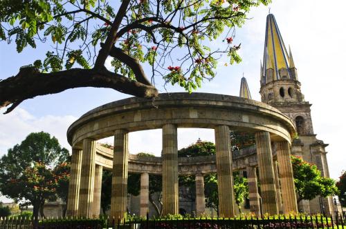a large building with a tree and a church at NH Guadalajara Studios in Guadalajara
