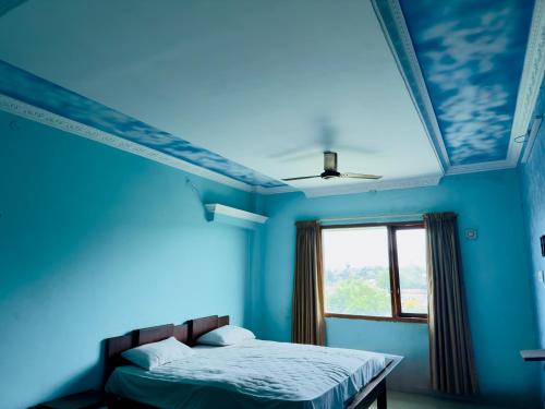 a blue bedroom with a bed and a window at Hotel City Towers, Nagore in kāraikāl