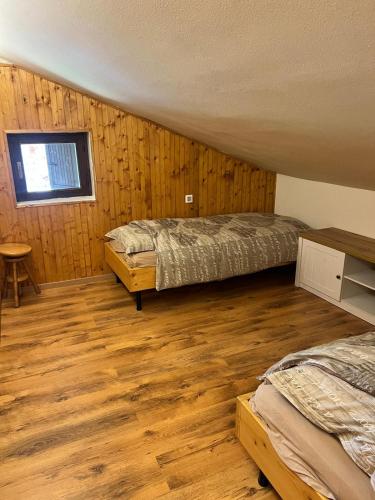 a bedroom with two beds and a window and wooden floors at Wood & Fire Chalet in Borno