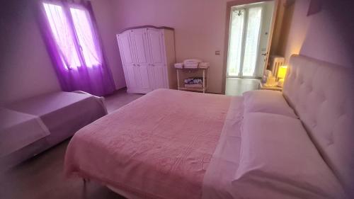 a bedroom with a white bed and two windows at Tana della Lavanda in Montefiorino