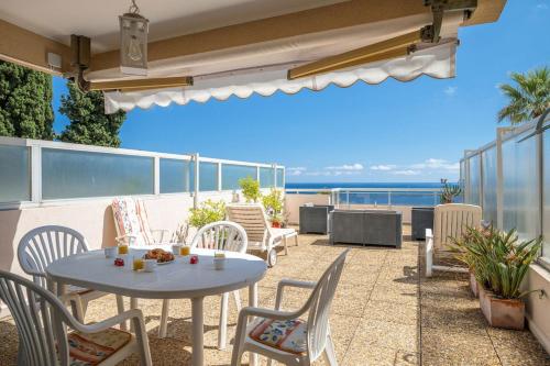 a patio with a table and chairs and the ocean at LE NEPTUNE - Vue Mer - Grande terrasse - Parking Privé in Menton