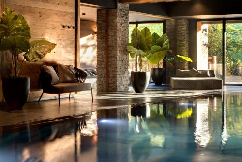 a swimming pool in a living room with plants at Domaine de Montagne - Hôtel Chalet Frère Joseph in Ventron