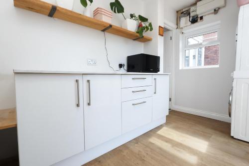 a kitchen with white cabinets and a window at Spacious 3 Bedroom Home in Heart Of Pontypool With Parking - By EKLIVING LUXE Short Lets & Serviced Accommodation in Griffithstown