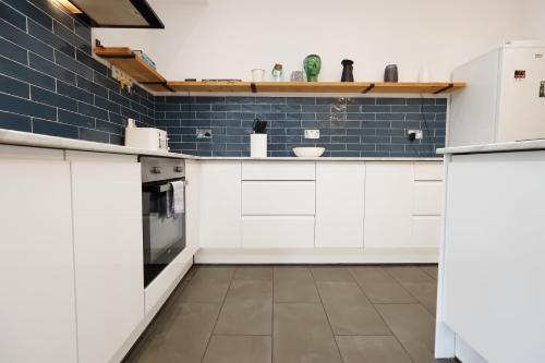 a kitchen with white cabinets and blue subway tiles at Spacious 3 Bedroom Home in Heart Of Pontypool With Parking - By EKLIVING LUXE Short Lets & Serviced Accommodation in Griffithstown