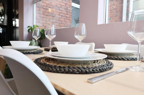 a wooden table with plates and glasses on it at Spacious 3 Bedroom Home in Heart Of Pontypool With Parking - By EKLIVING LUXE Short Lets & Serviced Accommodation in Griffithstown