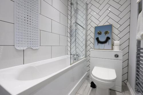 a white bathroom with a toilet and a bath tub at Spacious 3 Bedroom Home in Heart Of Pontypool With Parking - By EKLIVING LUXE Short Lets & Serviced Accommodation in Griffithstown